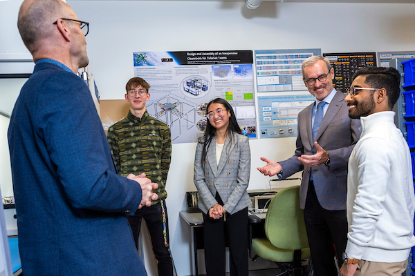 President Bill Flanagan speaking with four students.